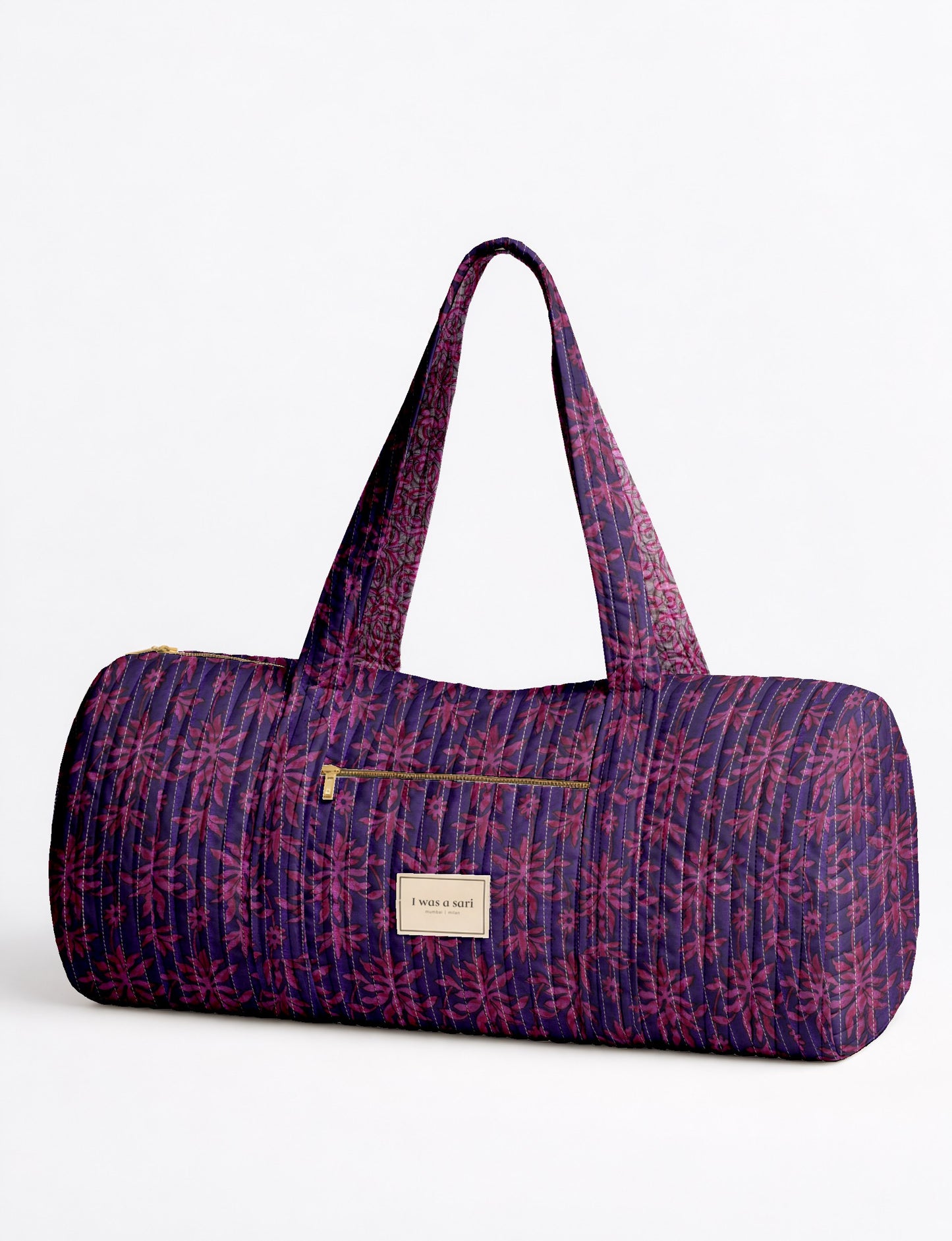 Quilted purple bowling bag with pink leaf pattern, front zipper pocket, and fabric label reading "I was a sari"