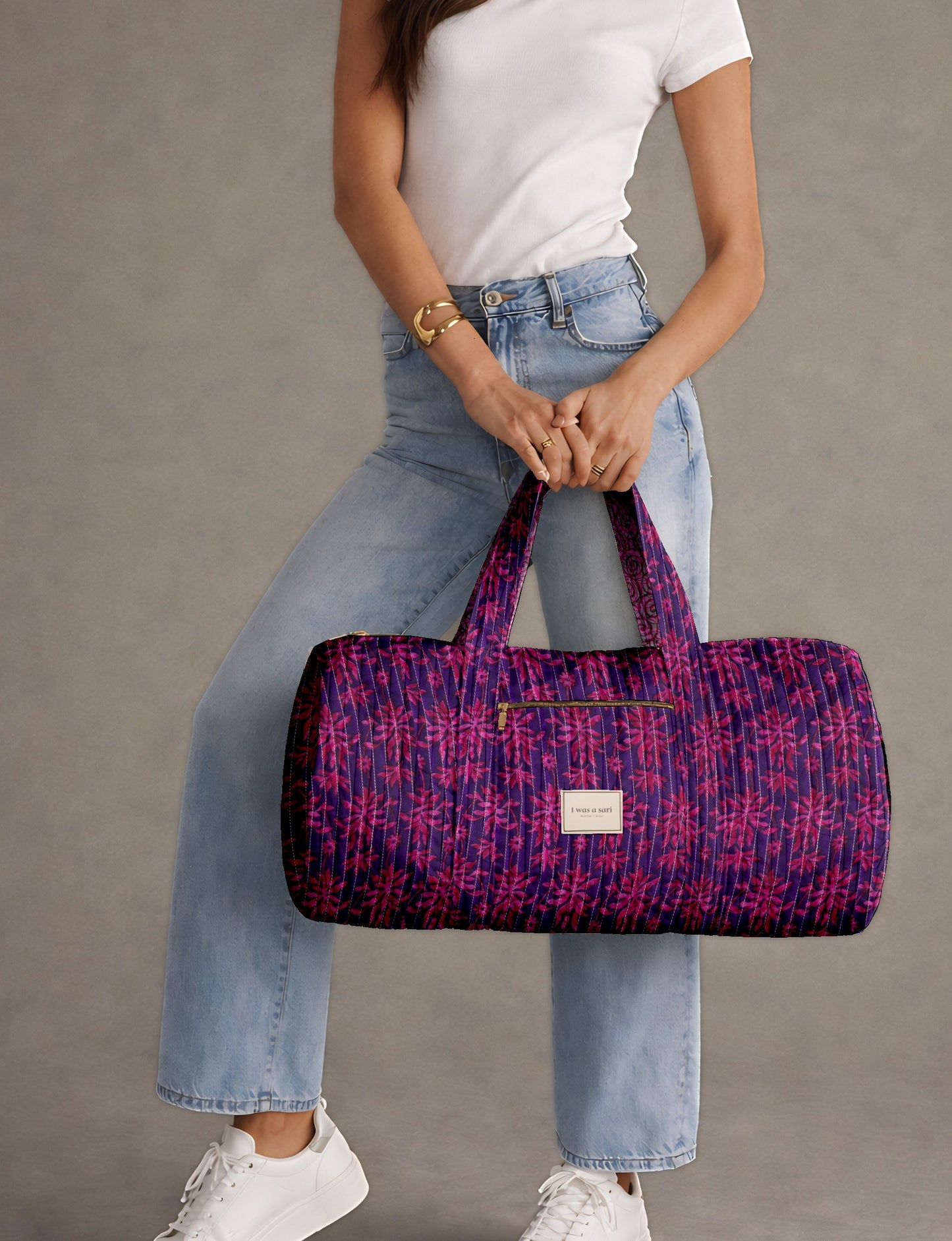 Woman wearing white t-shirt and light blue jeans holding a purple quilted bowling bag with pink leaf pattern and front