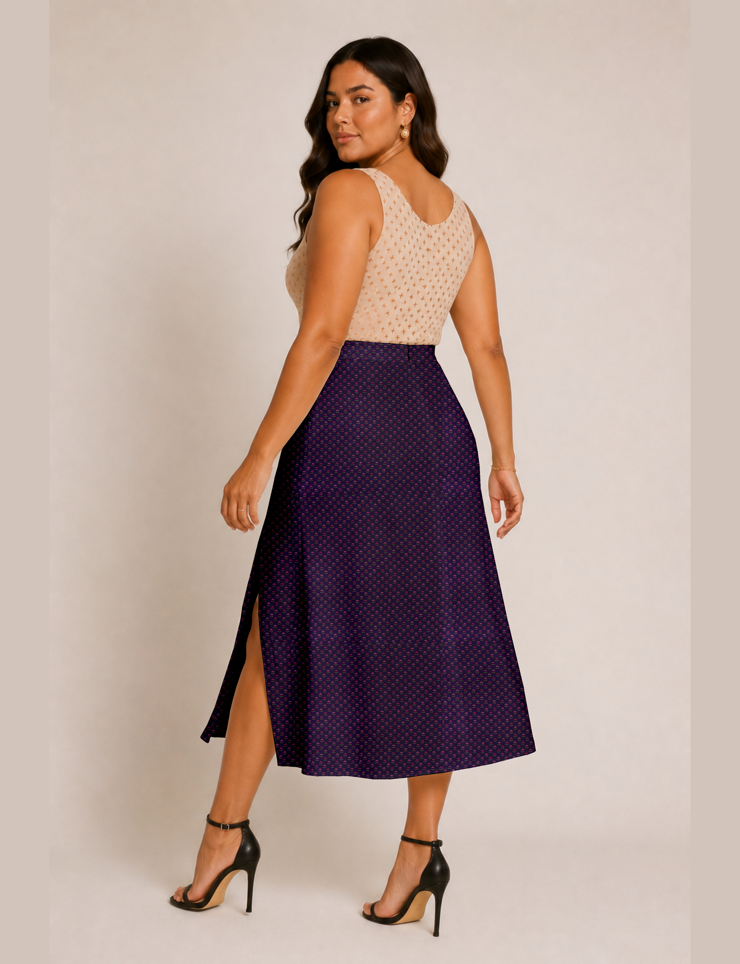 Woman wearing a yellow and black micro patterned A-line skirt with front slit, paired with beige sleeveless top and black