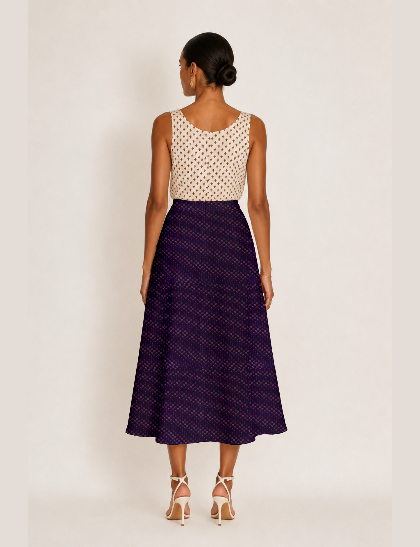 Woman wearing a yellow and black micro patterned A-line skirt with front slit, paired with beige sleeveless top and black