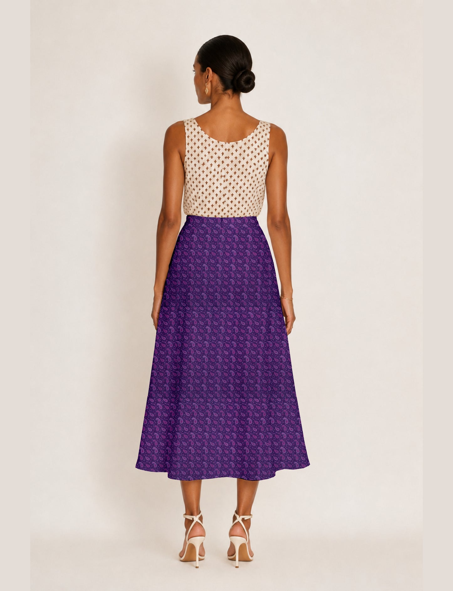 Woman wearing a yellow and navy blue A-line skirt with a slit and a sleeveless beige top with brown micro print