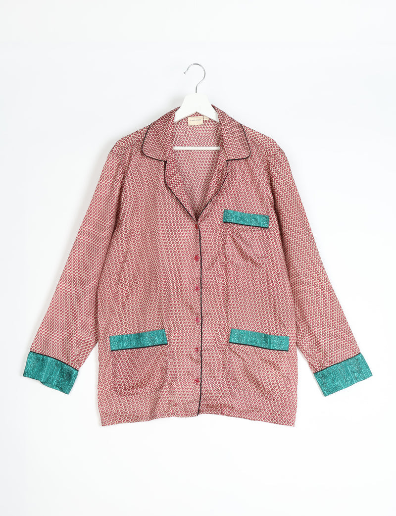 Beige long-sleeve pajama top with red micro pattern, teal paisley pocket and cuff accents, black piping, hanging on white hanger