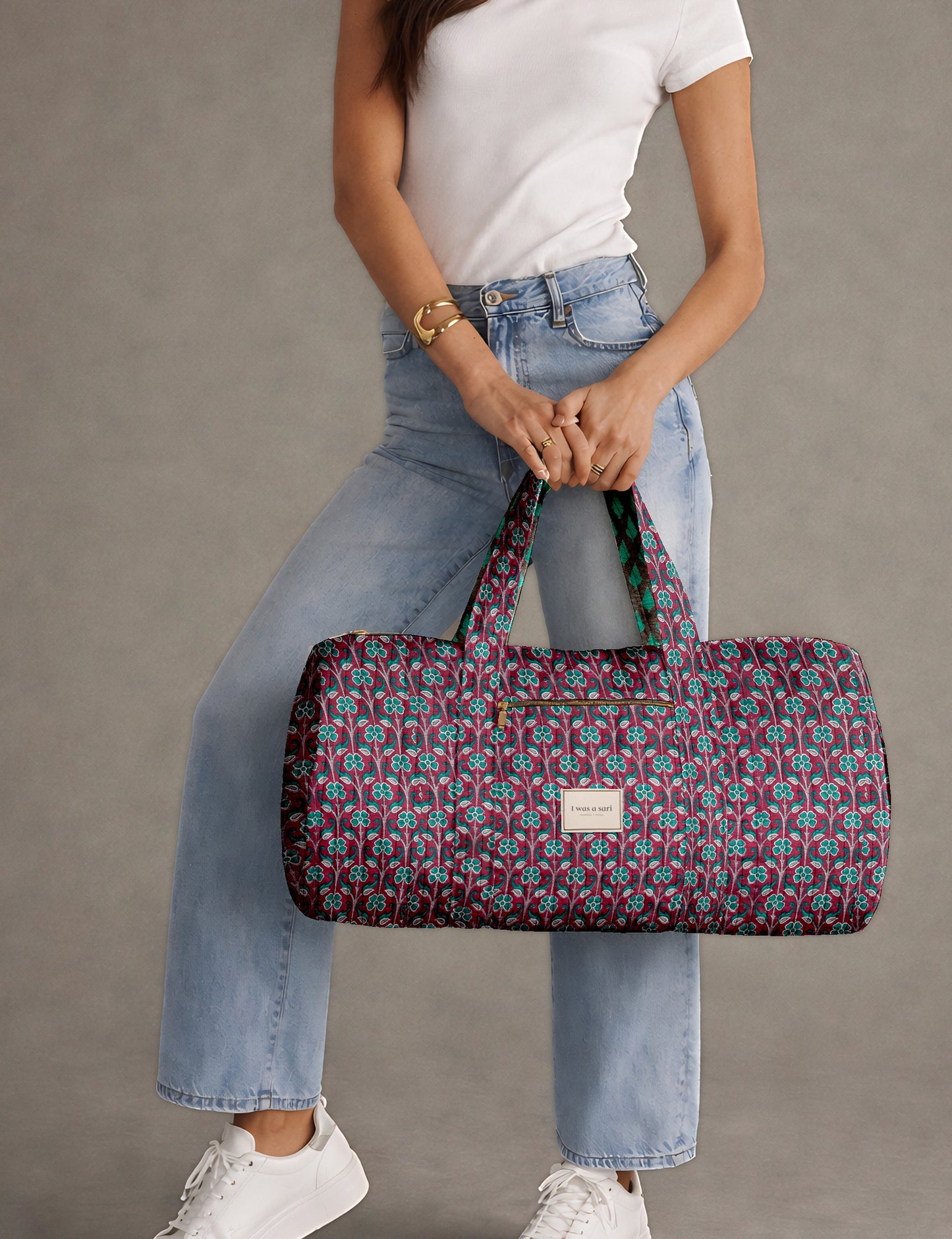 Brown paisley quilted bowling bag with front zipper pocket, held by person wearing white shirt and light blue jeans