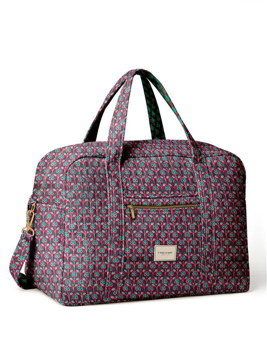 Brown quilted duffle bag with paisley pattern, front zip pocket, dual handles, and label reading "I was a sari"