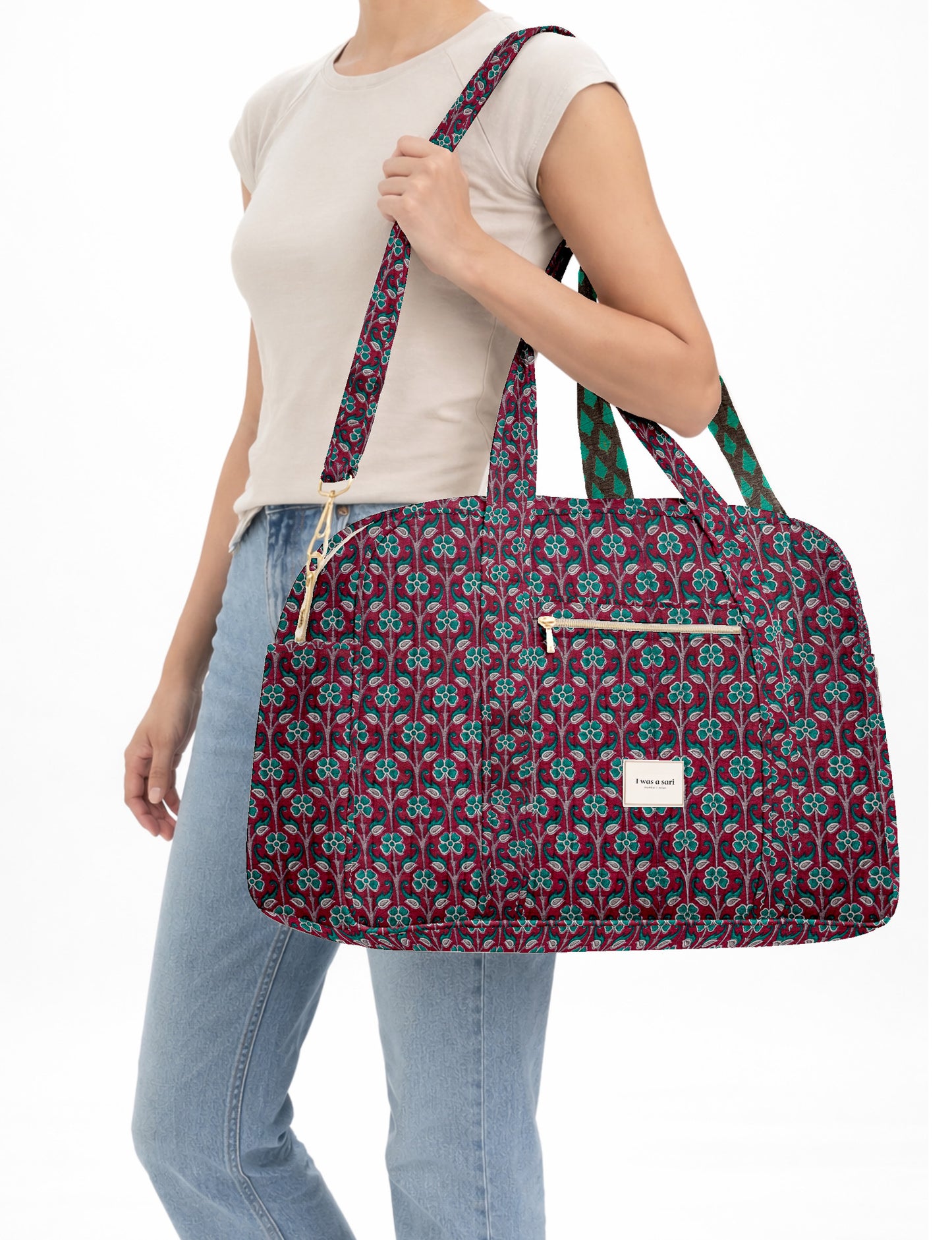 Brown quilted duffle bag with paisley pattern, front zip pocket, dual handles, and label reading "I was a sari"