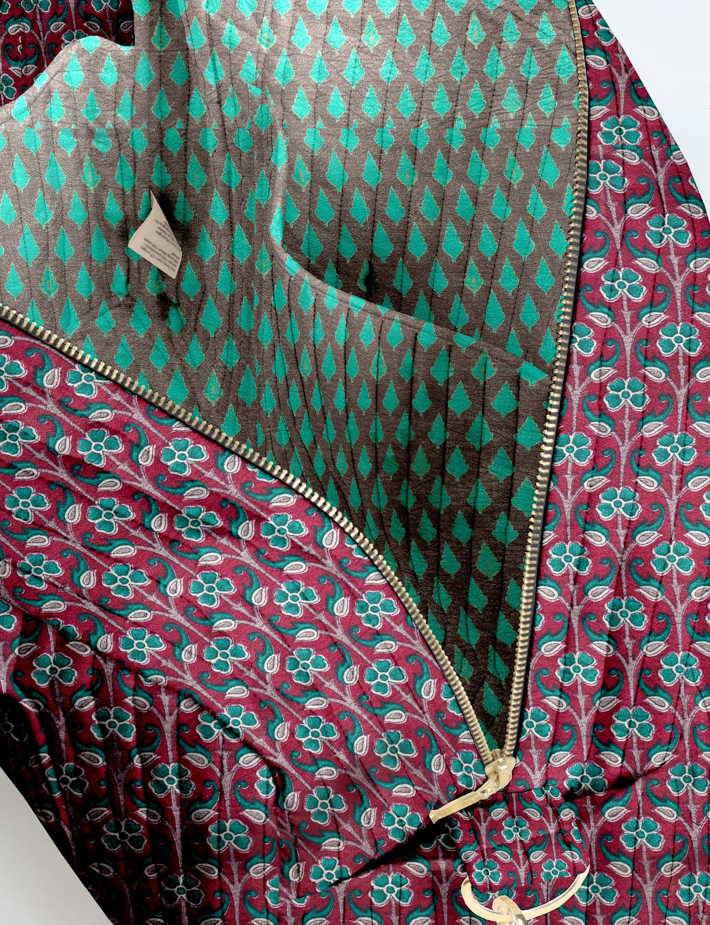 Brown quilted duffle bag with paisley pattern, front zip pocket, dual handles, and label reading "I was a sari"