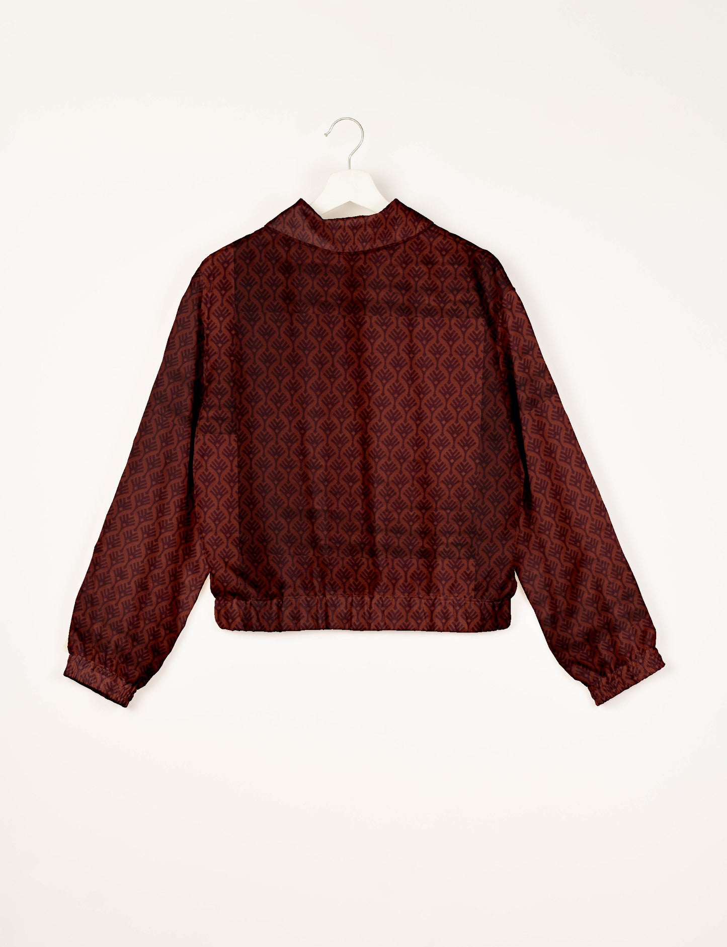 Red bomber jacket with dark leaf pattern, elastic cuffs and waistband, shown from back on white hanger