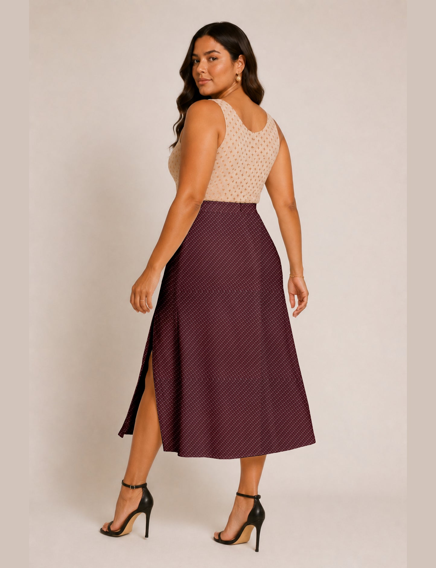 Woman wearing a yellow and black micro patterned A-line skirt with front slit, paired with beige sleeveless top and black