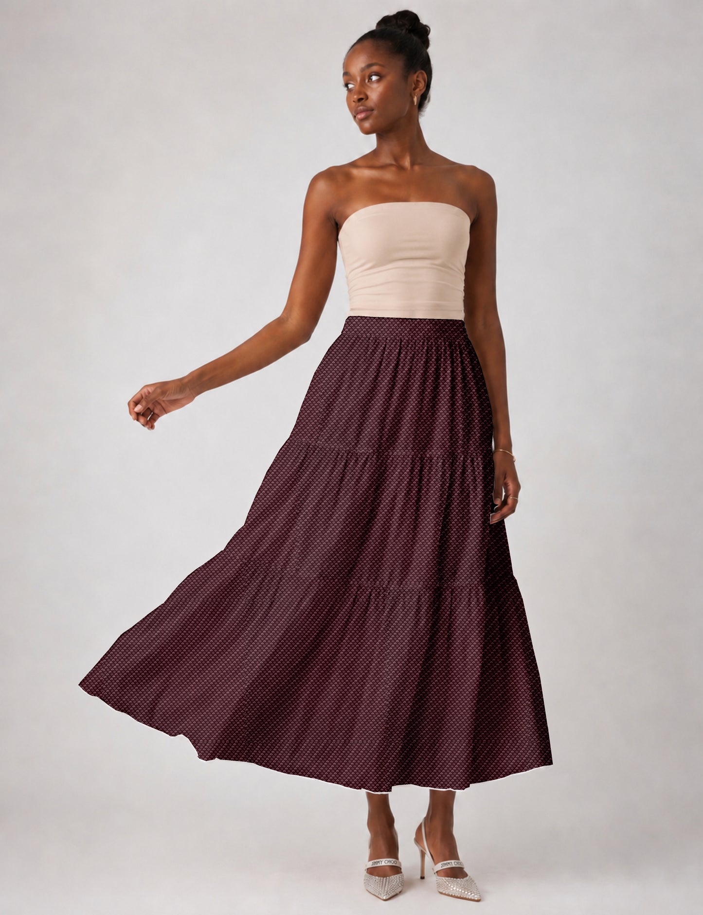 Woman wearing a yellow midi tiered skirt with a small geometric pattern, shown from the back, paired with beige top and