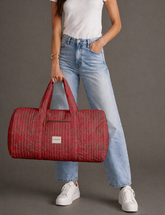 Quilted brown paisley barrel bag with double handles, front pocket, and gold zipper, shown in side angle view