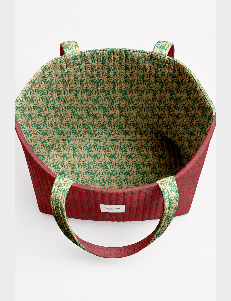 Quilted beach bag with yellow tropical exterior and red patterned interior, shown from top view with handles visible