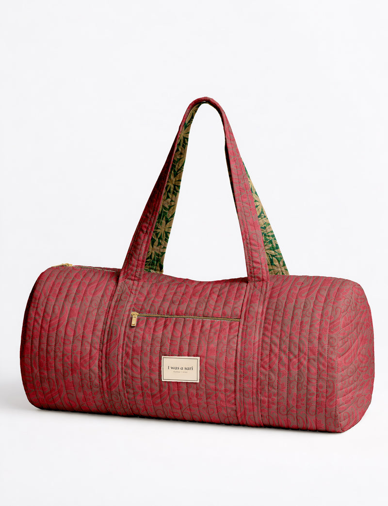 Brown paisley quilted bowling bag with front zipper pocket, held by person wearing white shirt and light blue jeans