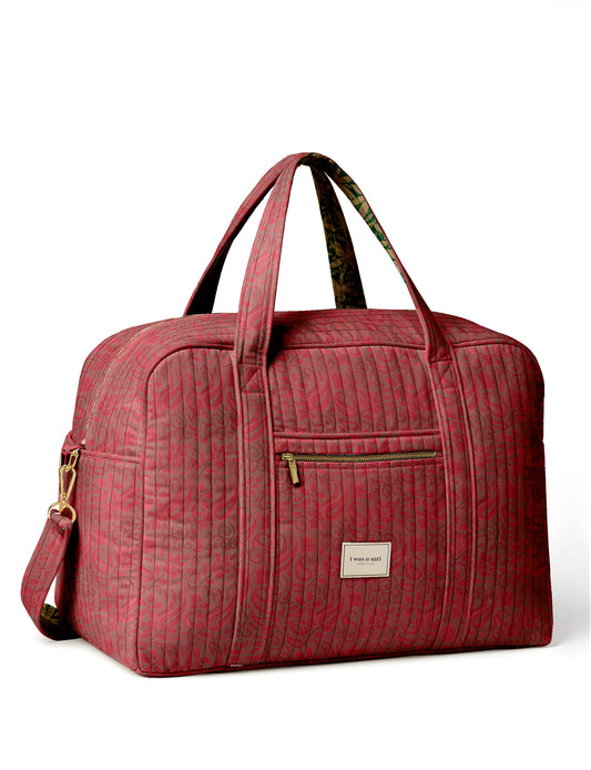 Brown quilted duffle bag with paisley pattern, front zip pocket, dual handles, and label reading "I was a sari"