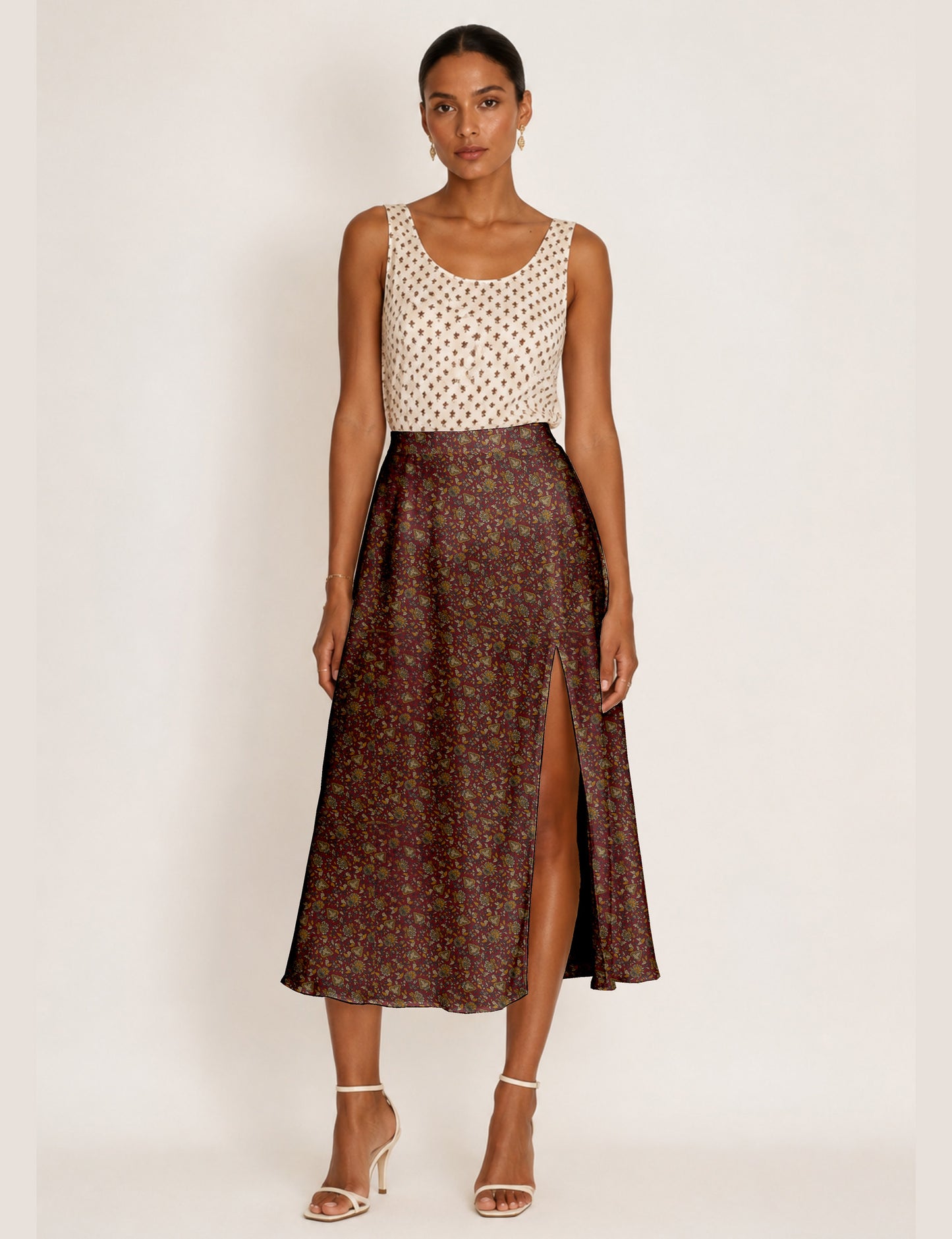 Woman wearing a yellow and black micro patterned A-line skirt with front slit, paired with beige sleeveless top and black