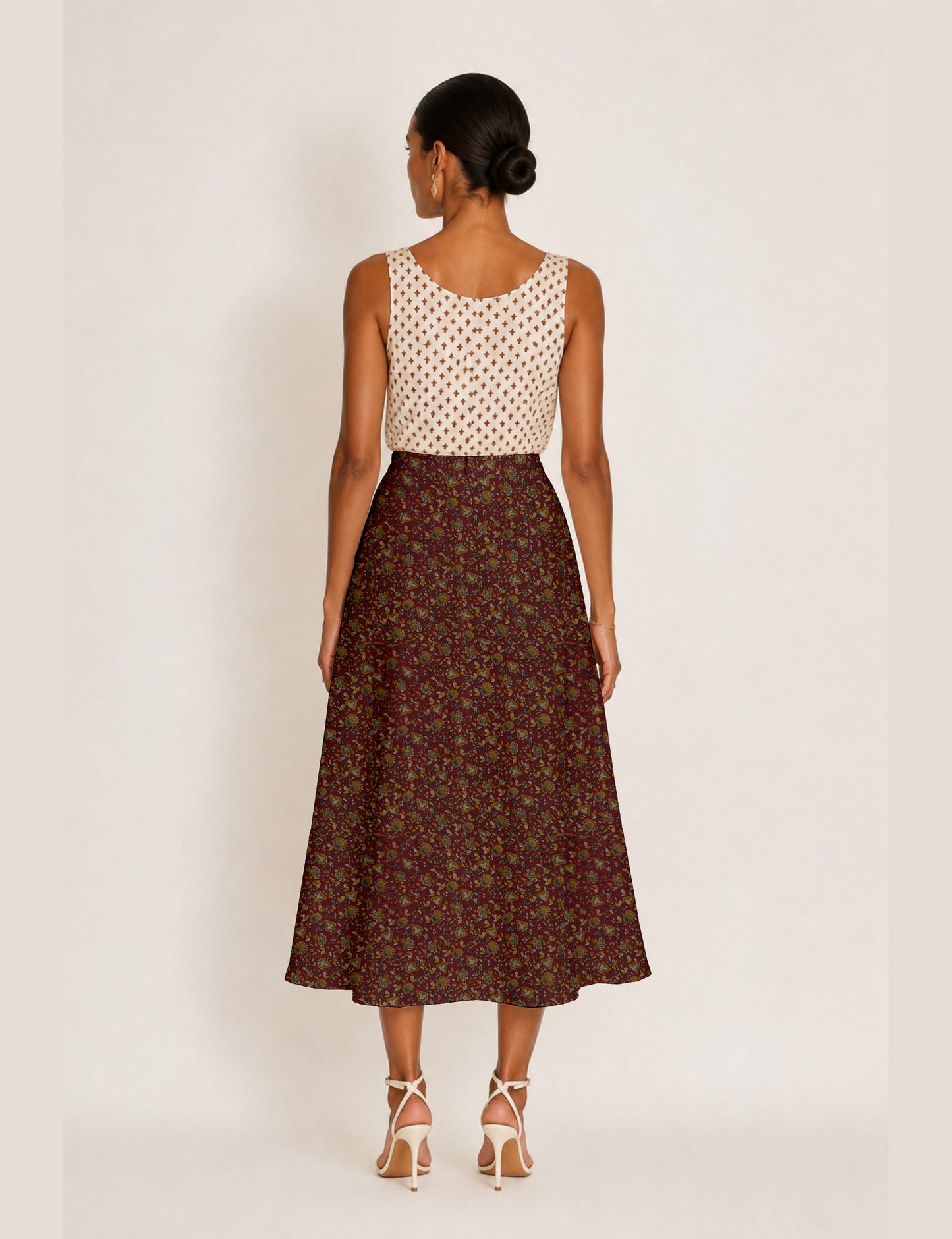 Woman wearing a yellow and black micro patterned A-line skirt with front slit, paired with beige sleeveless top and black