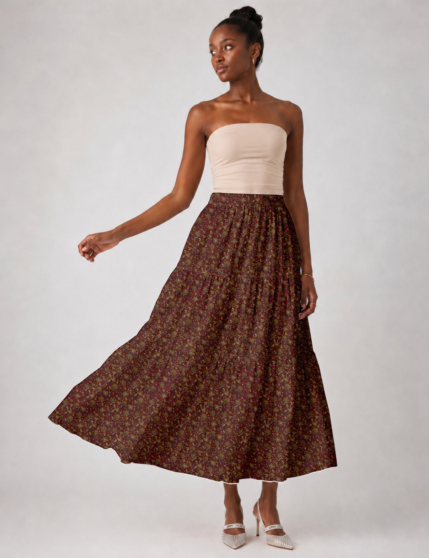 Woman wearing a yellow midi tiered skirt with a small geometric pattern, paired with a beige strapless top and white heels