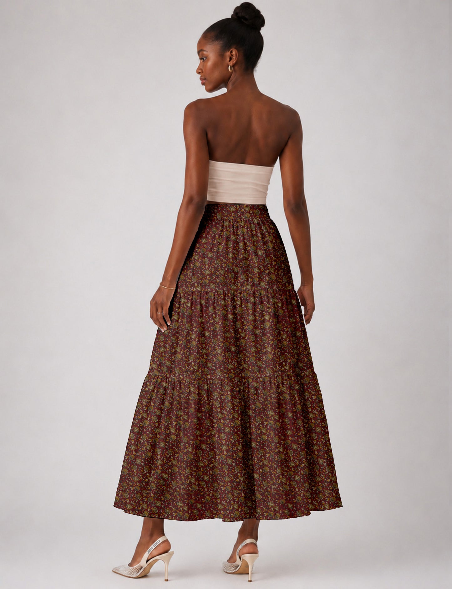 Woman wearing a yellow midi tiered skirt with a small geometric pattern, shown from the back, paired with beige top and