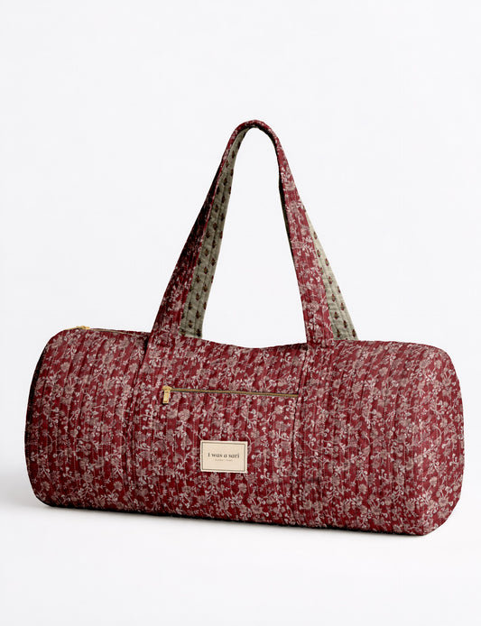 Quilted bowling bag by I Was A Sari with a structured design, featuring dual handles, zip closure, and a spacious interior with an outer zip pocket. Designed for everyday use and travel, it showcases a sleek elongated silhouette with functional storage and easy access compartments. Made from upcycled fabric, this sustainable handbag combines style and practicality, presented through detailed front, side, and lifestyle views.