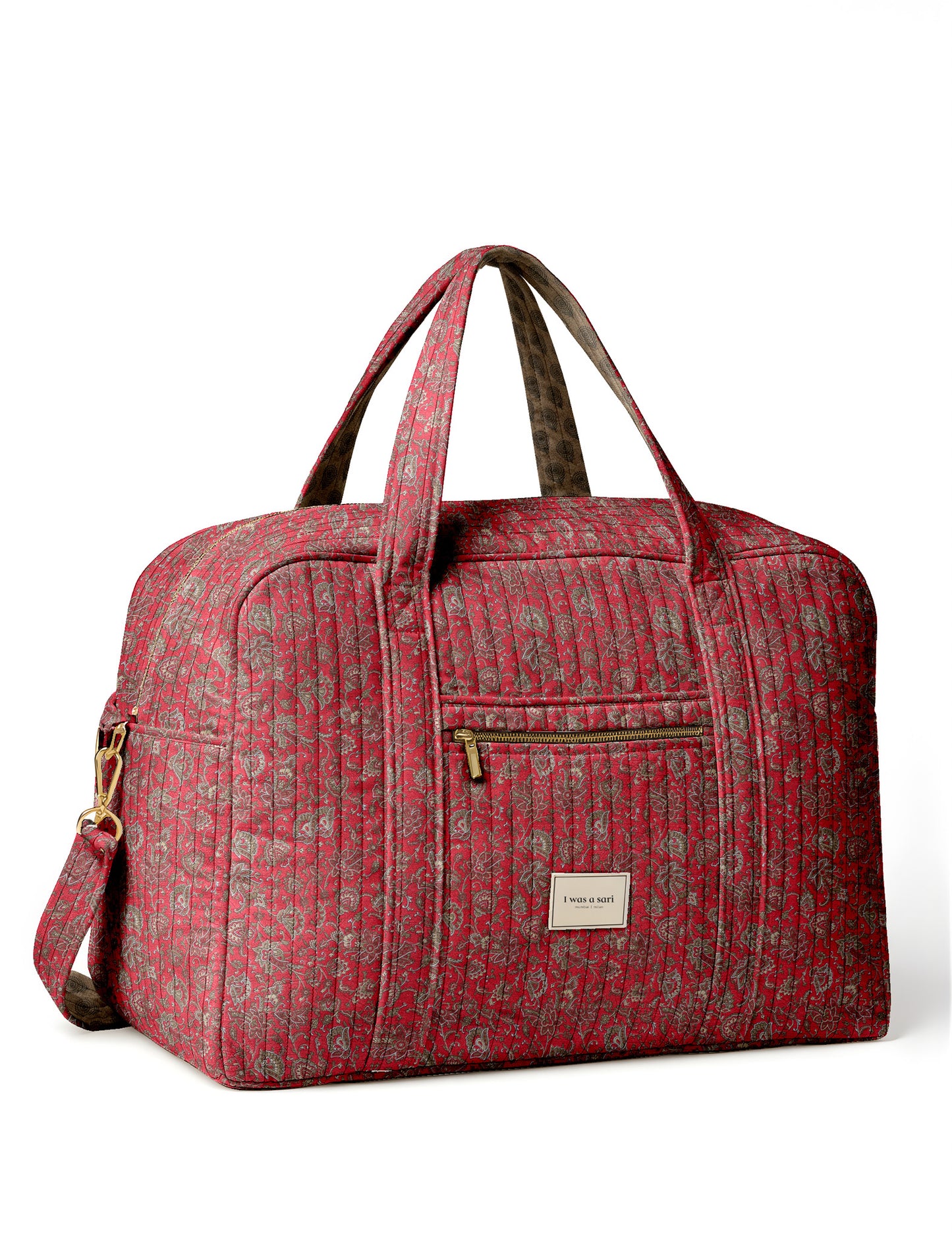 Brown quilted duffle bag with paisley pattern, front zip pocket, dual handles, and label reading "I was a sari"