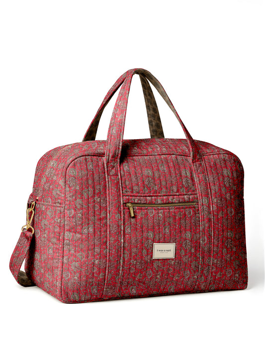 Brown quilted duffle bag with paisley pattern, front zip pocket, dual handles, and label reading "I was a sari"