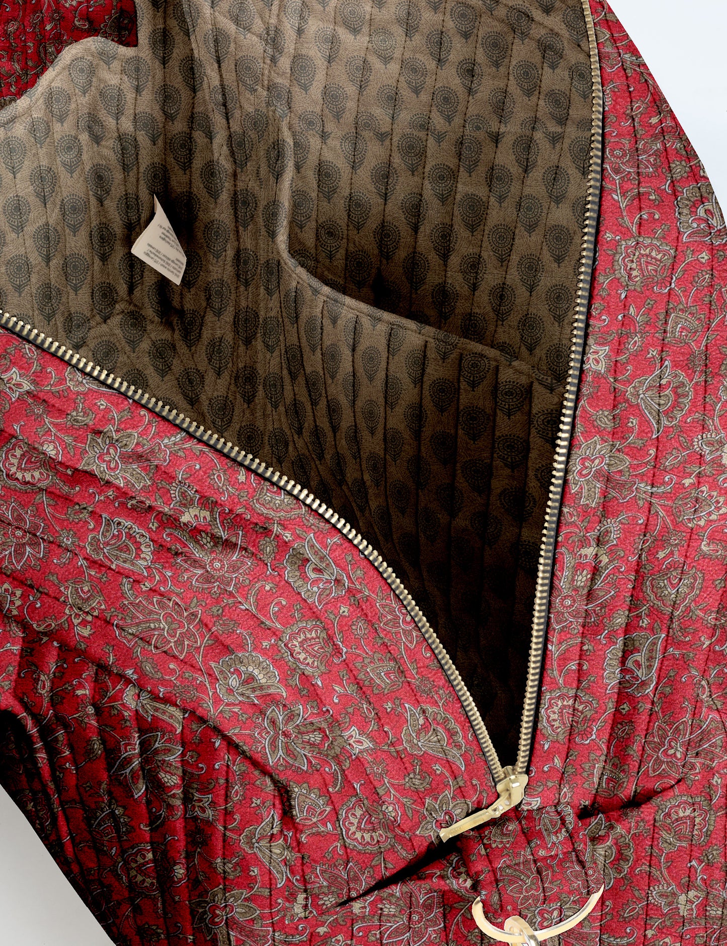 Brown quilted duffle bag with paisley pattern, front zip pocket, dual handles, and label reading "I was a sari"