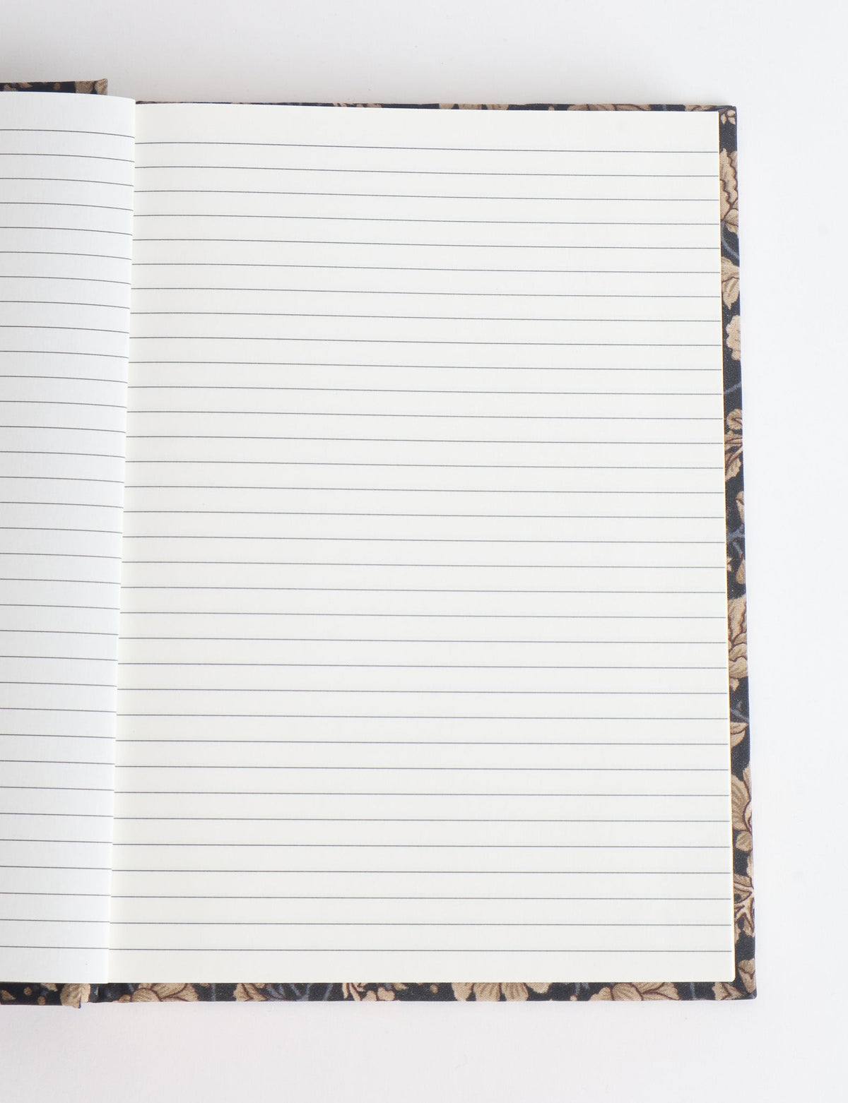 Open A5 hard cover notebook with blue and beige floral patterned edges and lined white pages, flat lay view