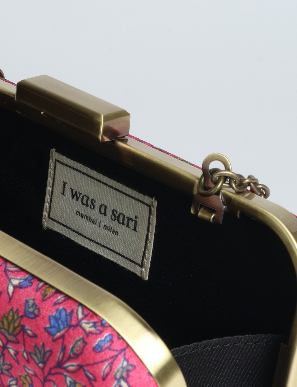Structured box clutch bag featuring a rigid metal frame, secure clasp closure, detachable metal chain strap, and compact rectangular silhouette.