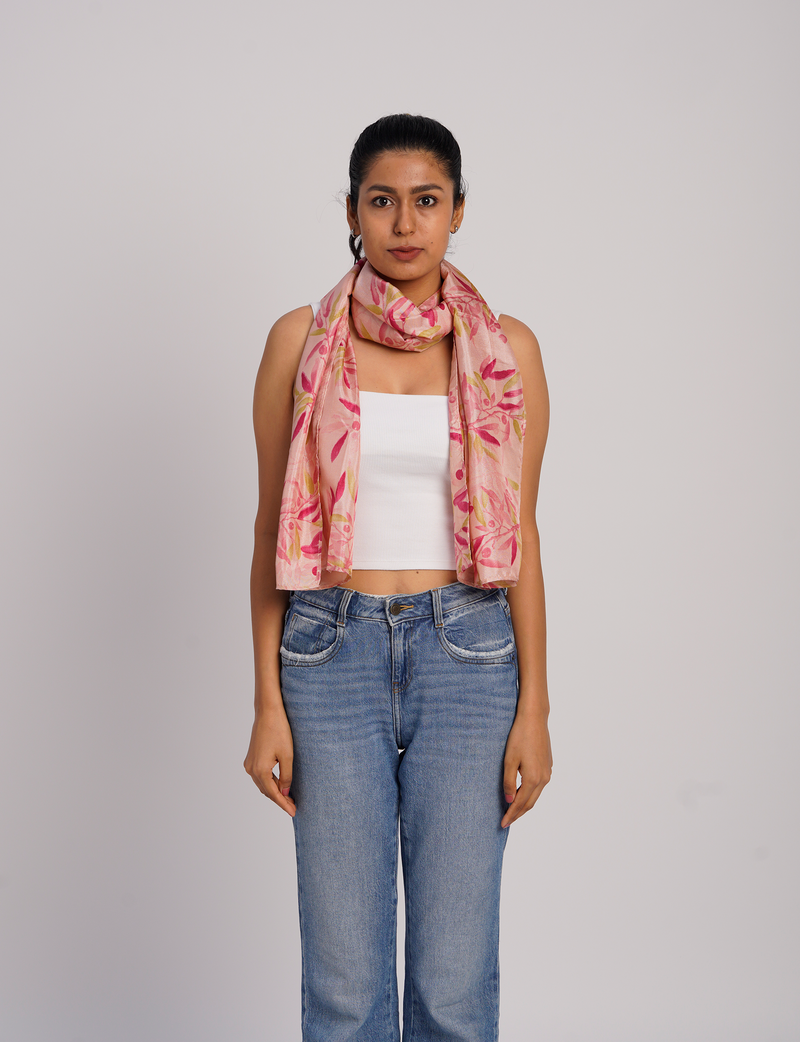 Woman wearing a pink stole with red and yellow floral print over a white sleeveless top and blue jeans, front view