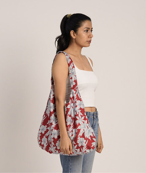 Woman wearing a red trapeze bag with large white floral geometric pattern over shoulder, side view