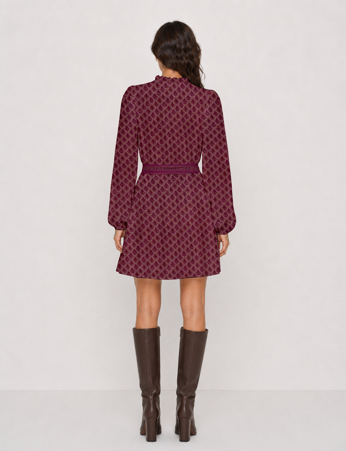 Woman wearing a pink swing dress with leaf pattern, long sleeves, scalloped neckline, and matching belt, shown from back