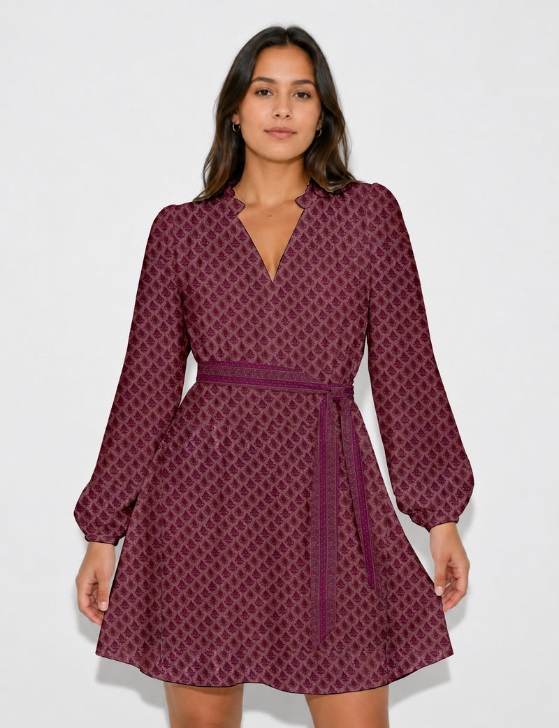 Woman wearing a pink swing dress with leaf pattern, long puff sleeves, scalloped V-neckline, and matching belt, front view
