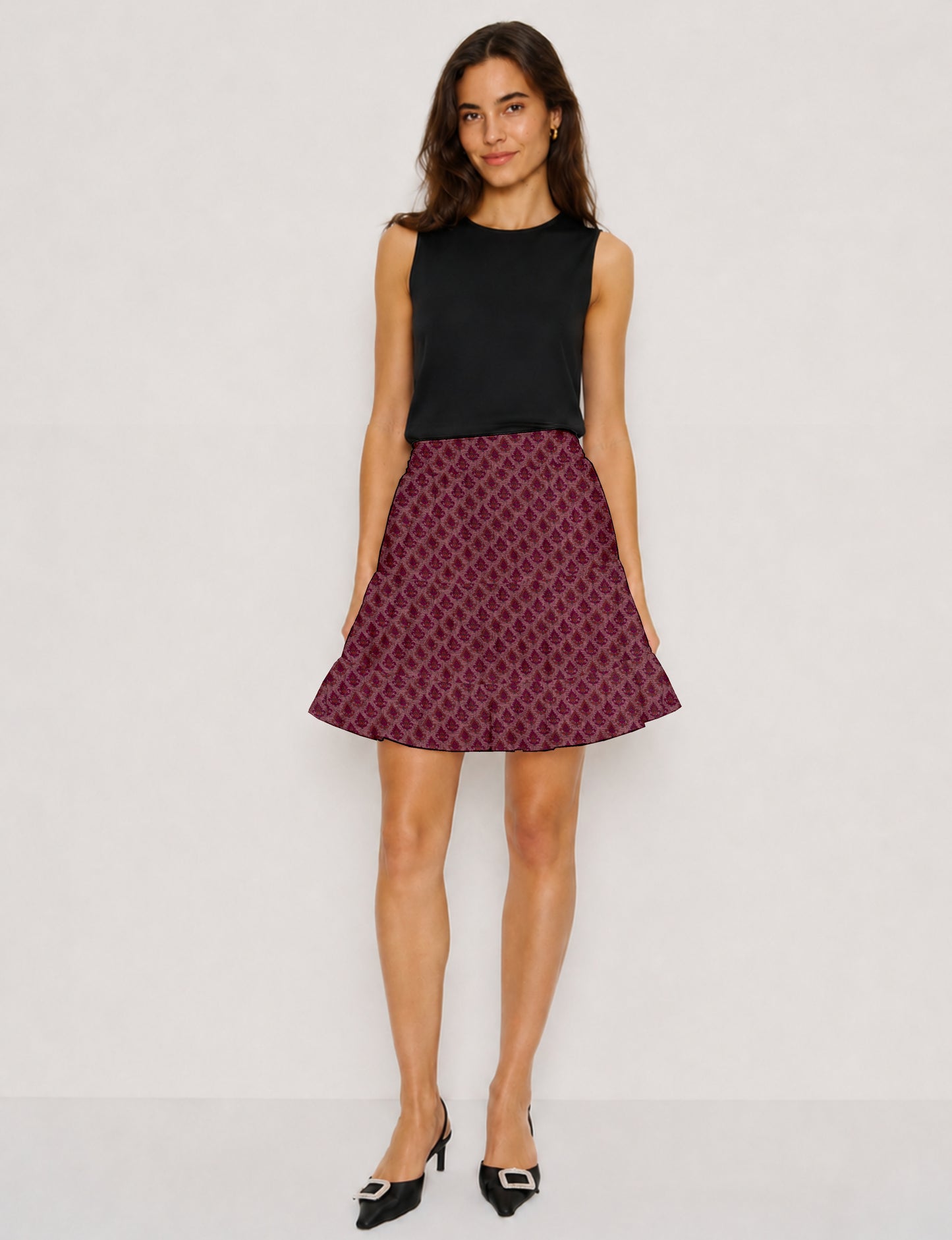 Woman wearing a short tiered skirt with pink leaf pattern, paired with a sleeveless black top and black heels with buckles