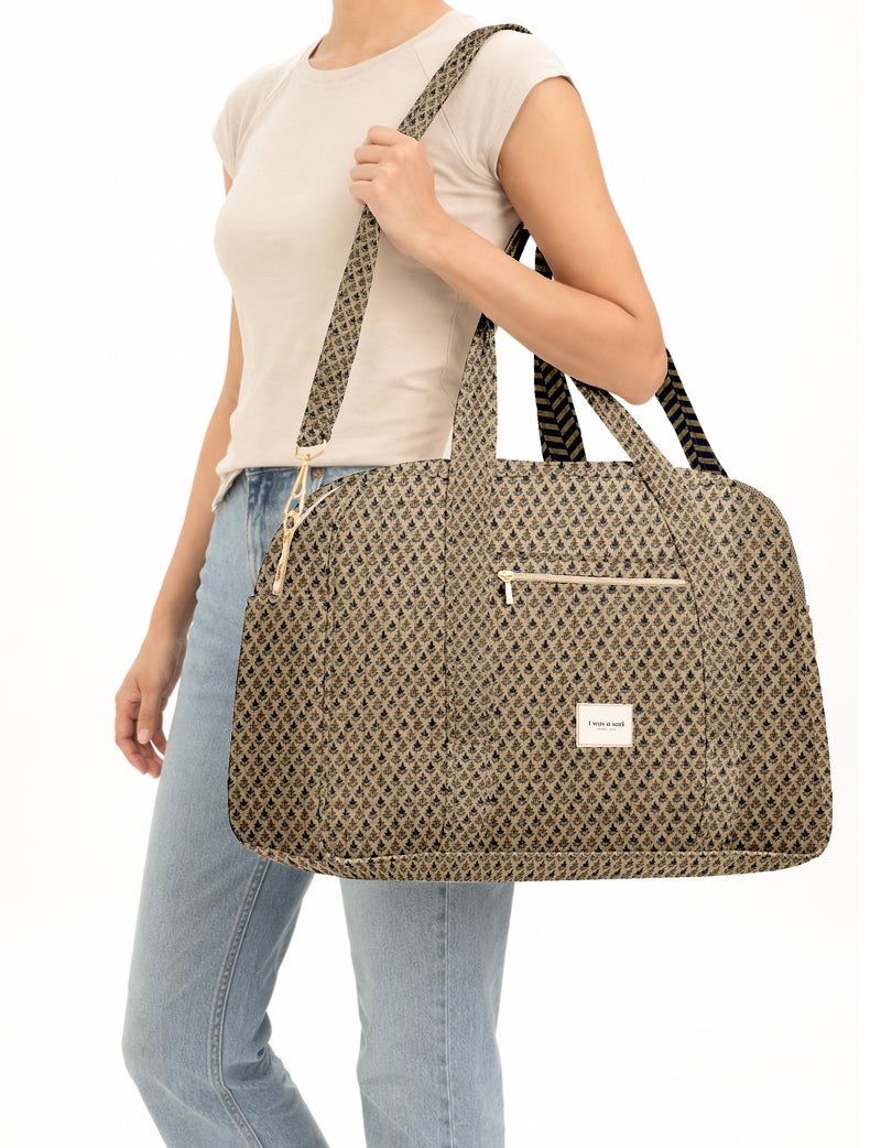 Woman wearing beige micro design quilted duffle bag with front zipper pocket and adjustable shoulder strap