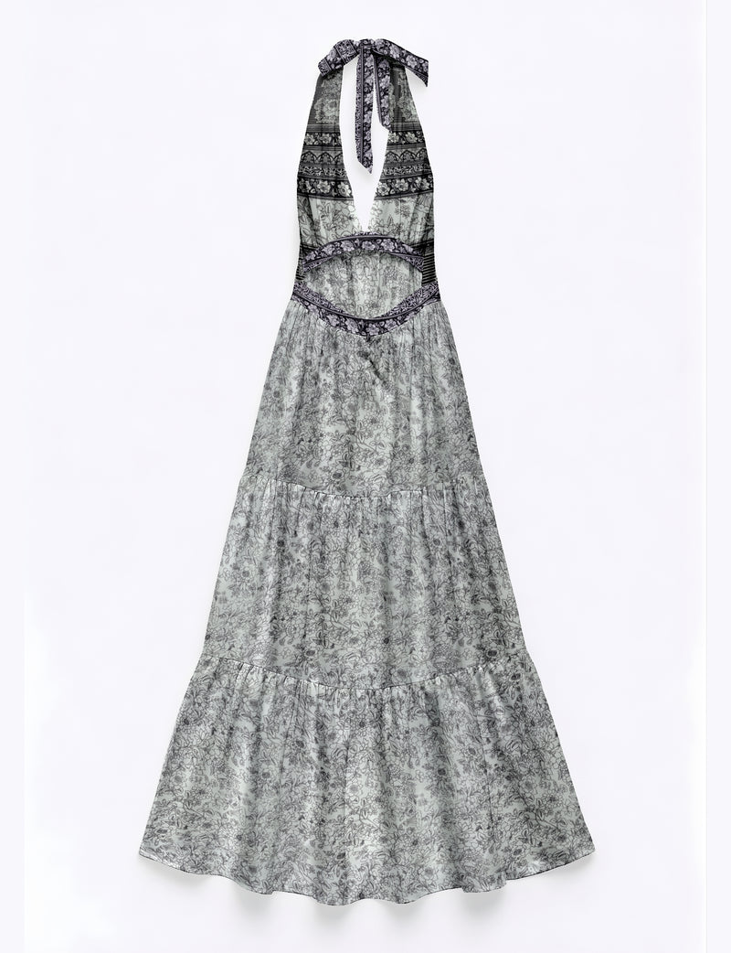 White maxi tiered dress with black floral and geometric patterns, halter neck tie, and cutout waist, flat lay view