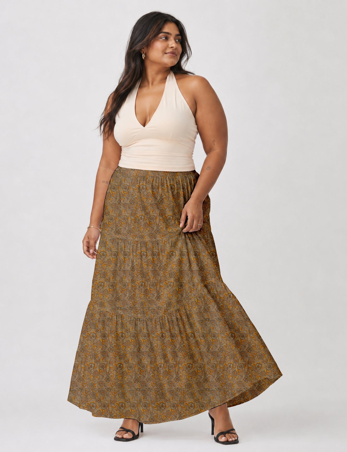 Woman wearing a yellow midi tiered skirt with a small geometric pattern, shown from the back, paired with beige top and