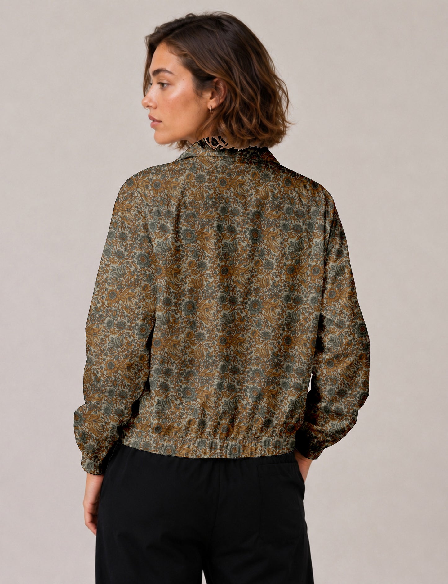 Woman wearing a yellow floral bomber jacket with front zipper, elastic cuffs, and side pockets, shown from front view