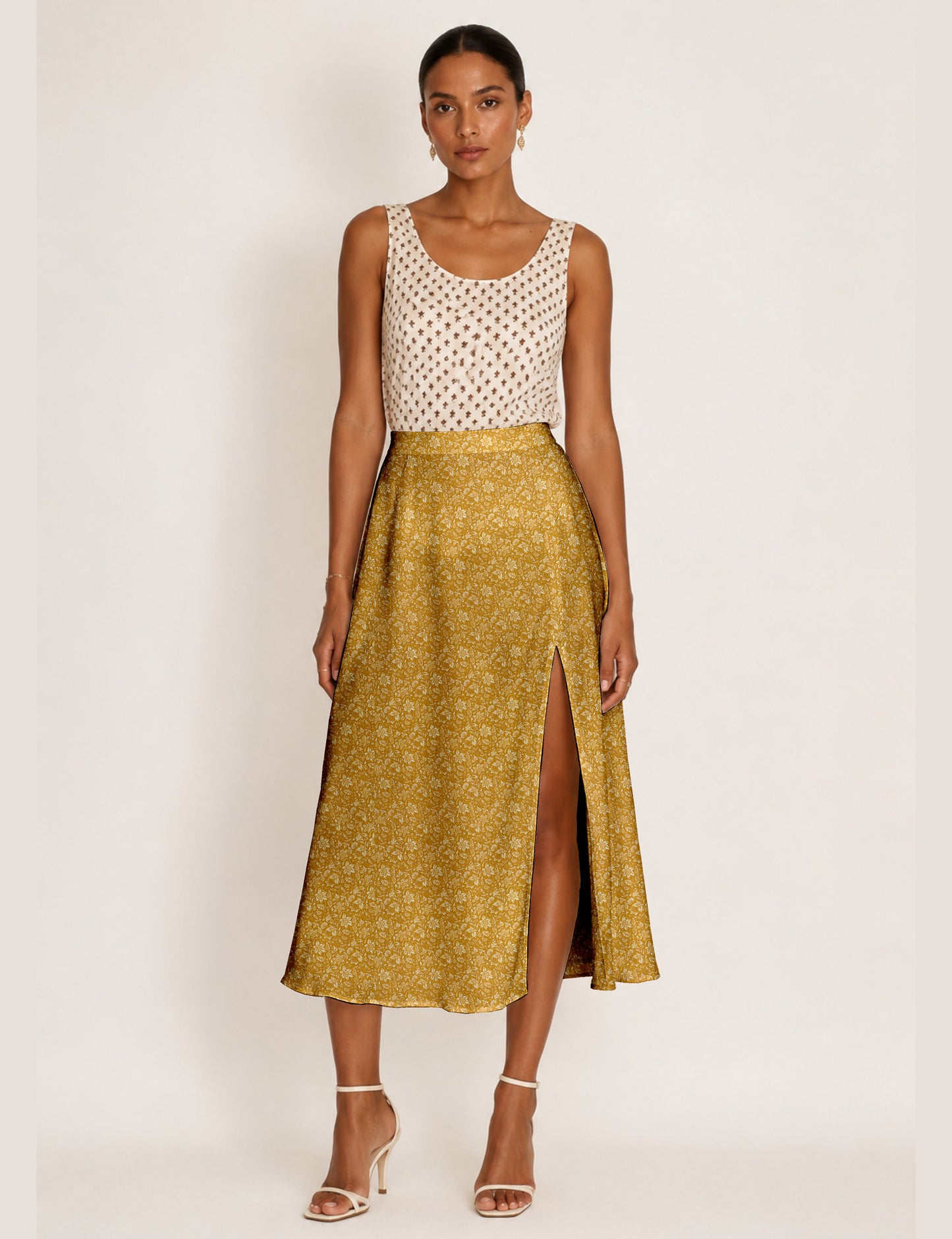 Woman wearing a yellow and black micro patterned A-line skirt with front slit, paired with beige sleeveless top and black