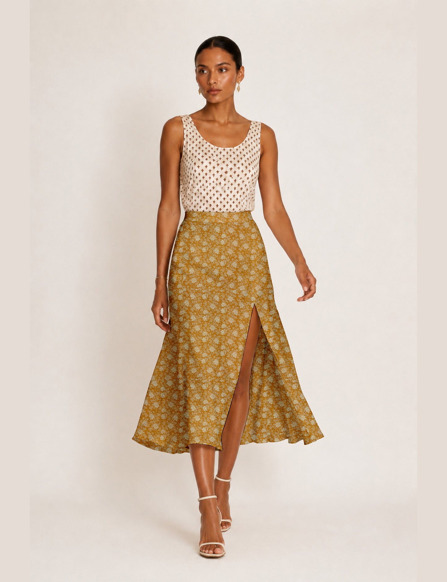 Woman wearing a yellow and black micro patterned A-line skirt with front slit, paired with beige sleeveless top and black