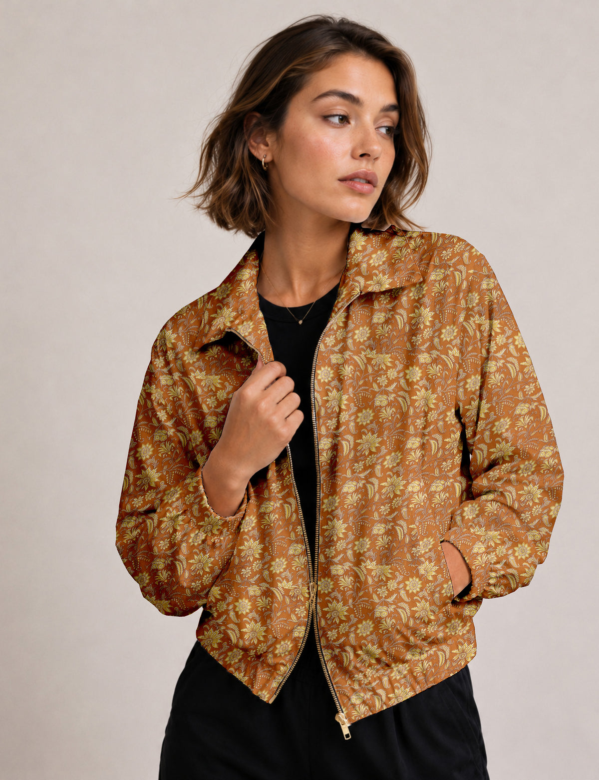 Woman wearing a yellow floral bomber jacket with front zipper, elastic cuffs, and side pockets, shown from front view