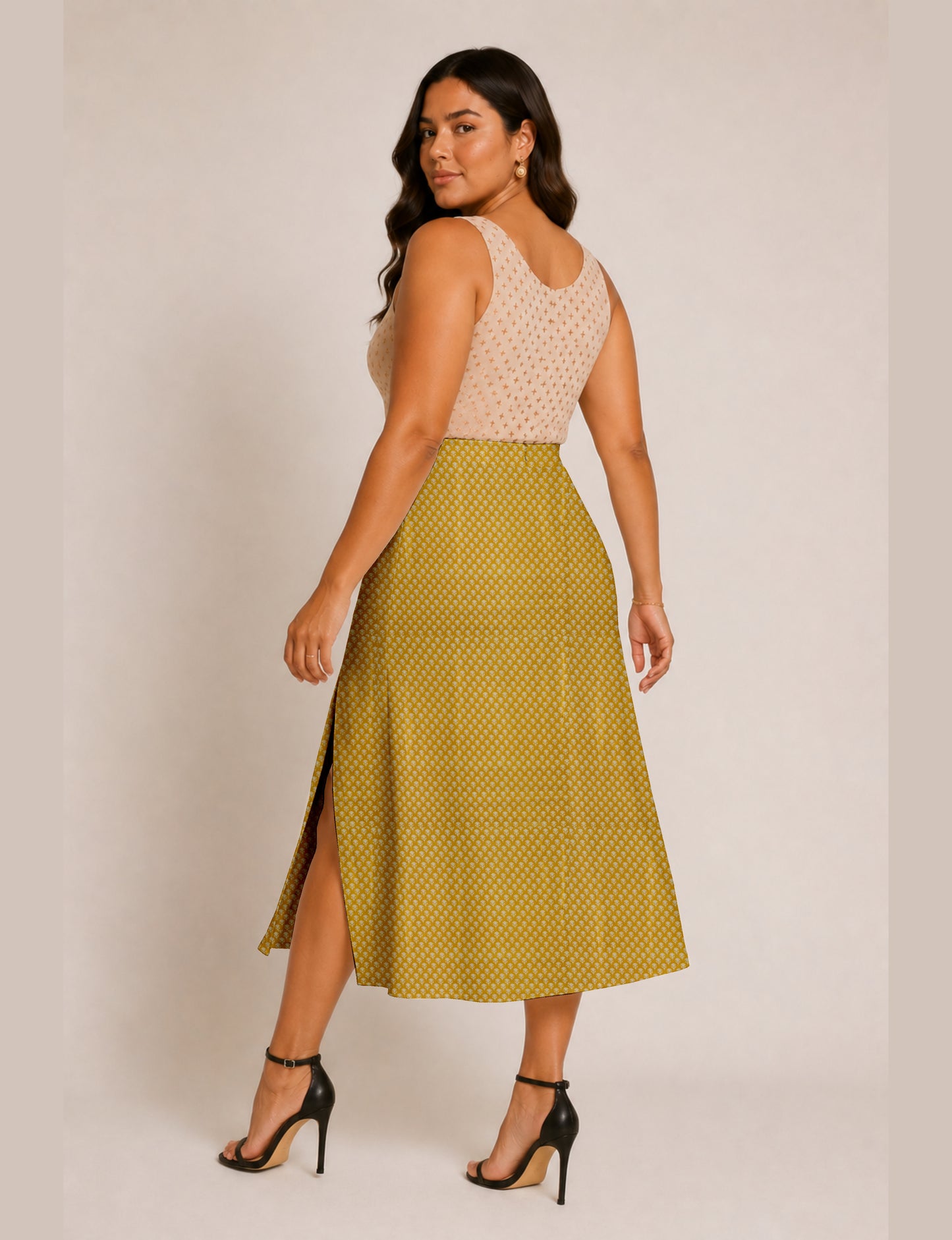 Woman wearing a yellow and black micro patterned A-line skirt with front slit, paired with beige sleeveless top and black