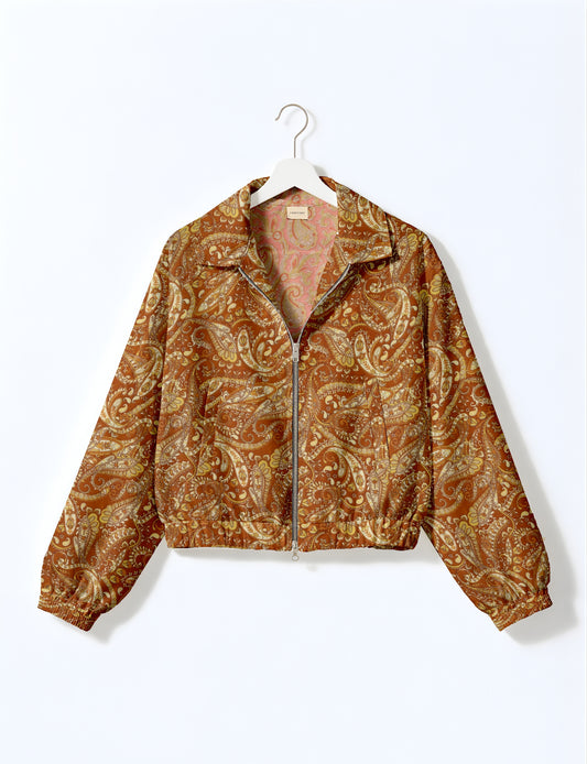 Brown paisley patterned bomber jacket with front zipper, elastic cuffs, and collar, hanging on white hanger against white