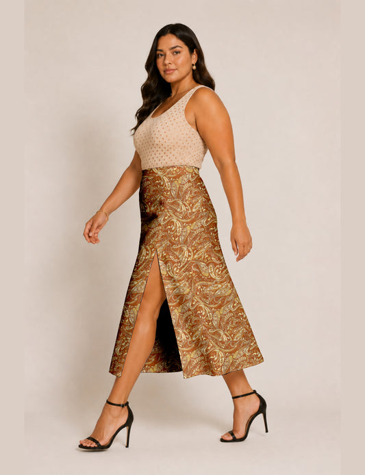 Woman wearing a brown and yellow paisley A-line skirt with front slit, paired with a beige sleeveless top and black heels