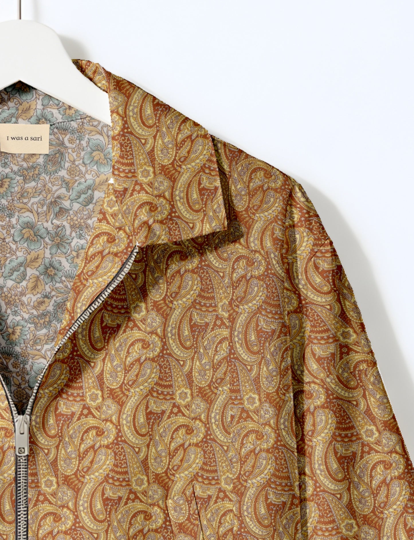 Women's cropped bomber jacket with twin metallic front zippers, welt pockets, elasticated hem and cuffs, and contrast sari print lining.