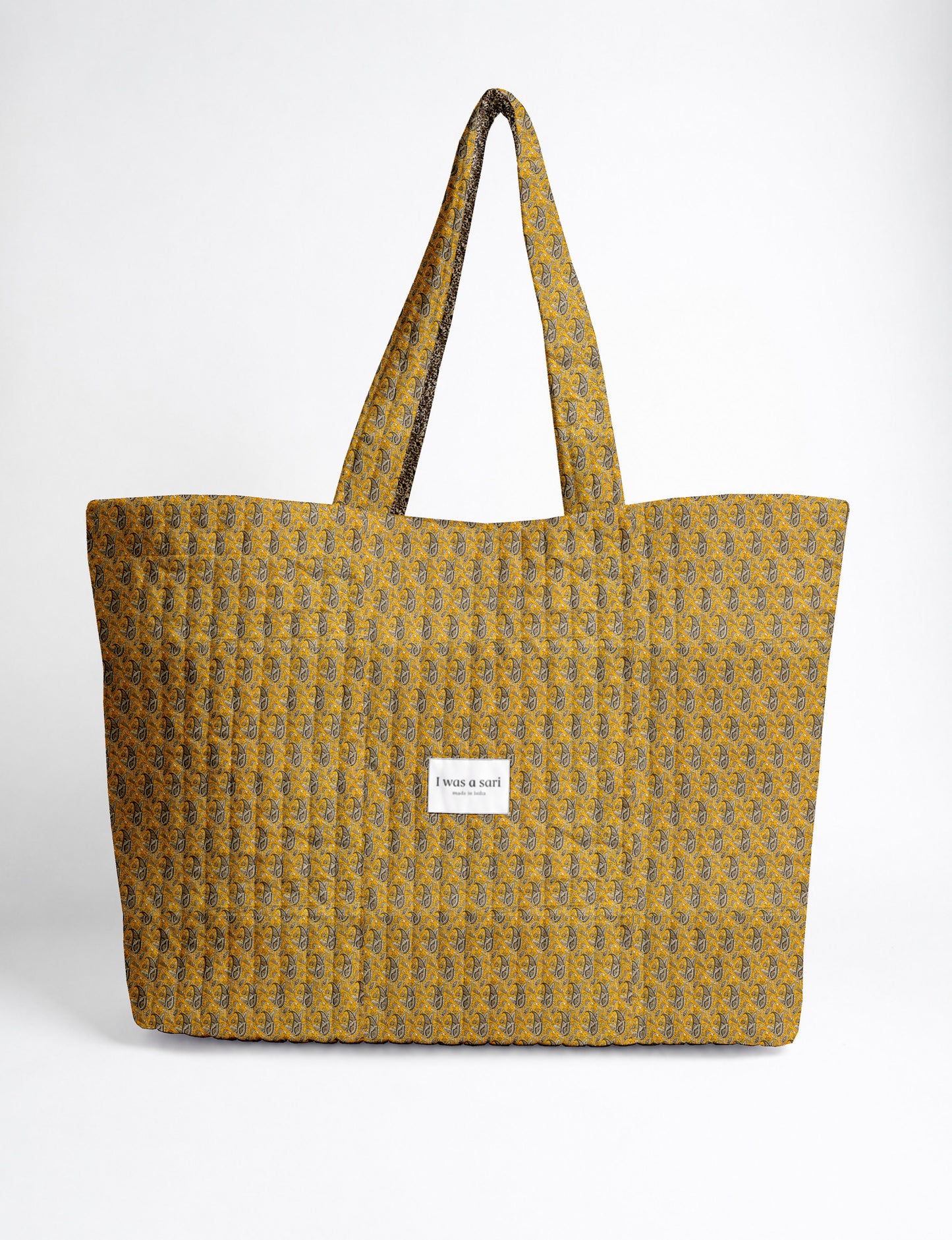 Quilted yellow tropical patterned beach bag with long handles and white label reading "I was a sari" front view