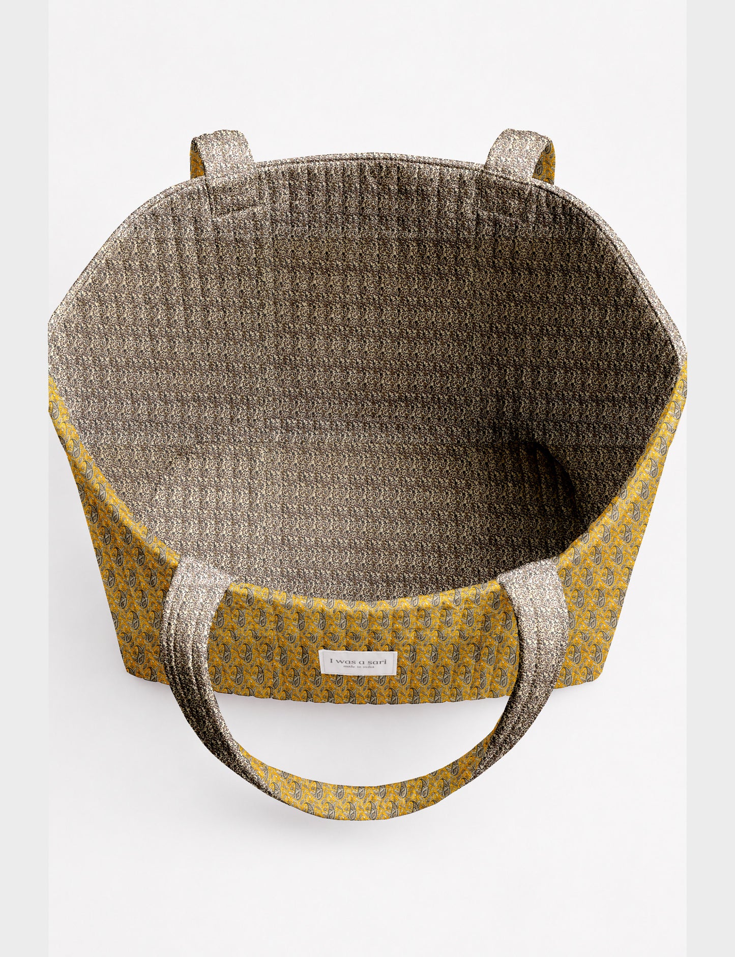 Quilted beach bag with yellow tropical exterior and red patterned interior, shown from top view with handles visible