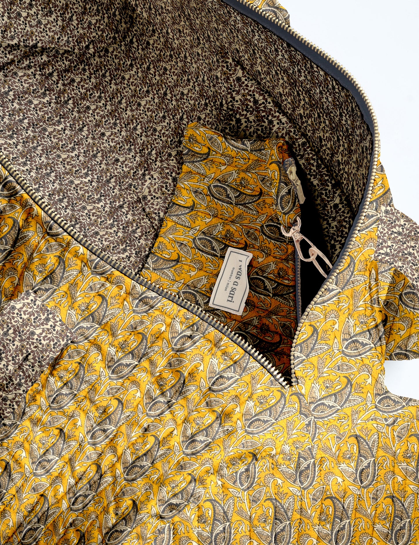 Brown paisley quilted bowling bag with front zipper pocket, held by person wearing white shirt and light blue jeans