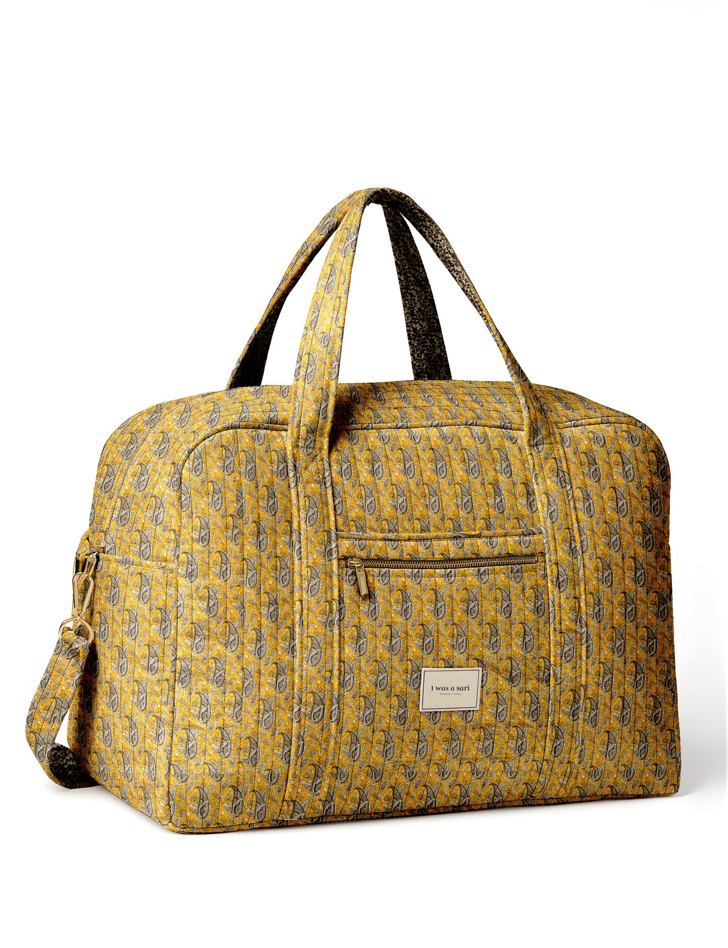 Brown quilted duffle bag with paisley pattern, front zip pocket, dual handles, and label reading "I was a sari"