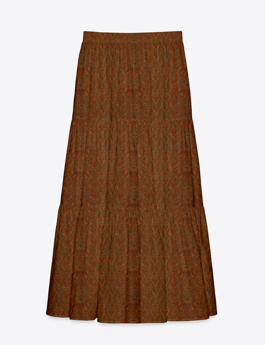 Woman wearing a yellow midi tiered skirt with a small geometric pattern, paired with a beige strapless top and white heels