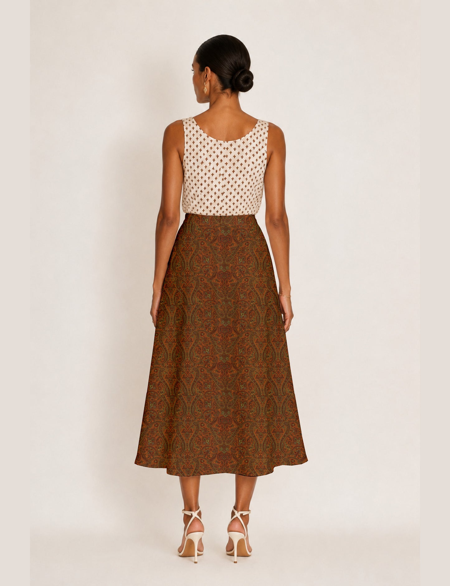 Woman wearing a yellow and black micro patterned A-line skirt with front slit, paired with beige sleeveless top and black