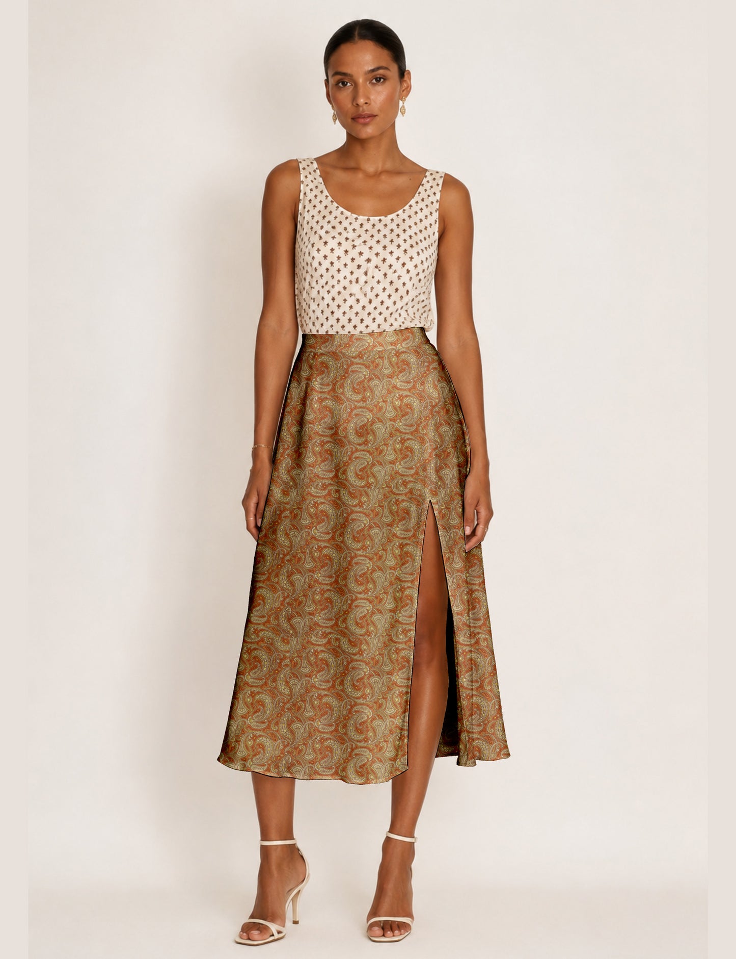Woman wearing a yellow and black micro patterned A-line skirt with front slit, paired with beige sleeveless top and black